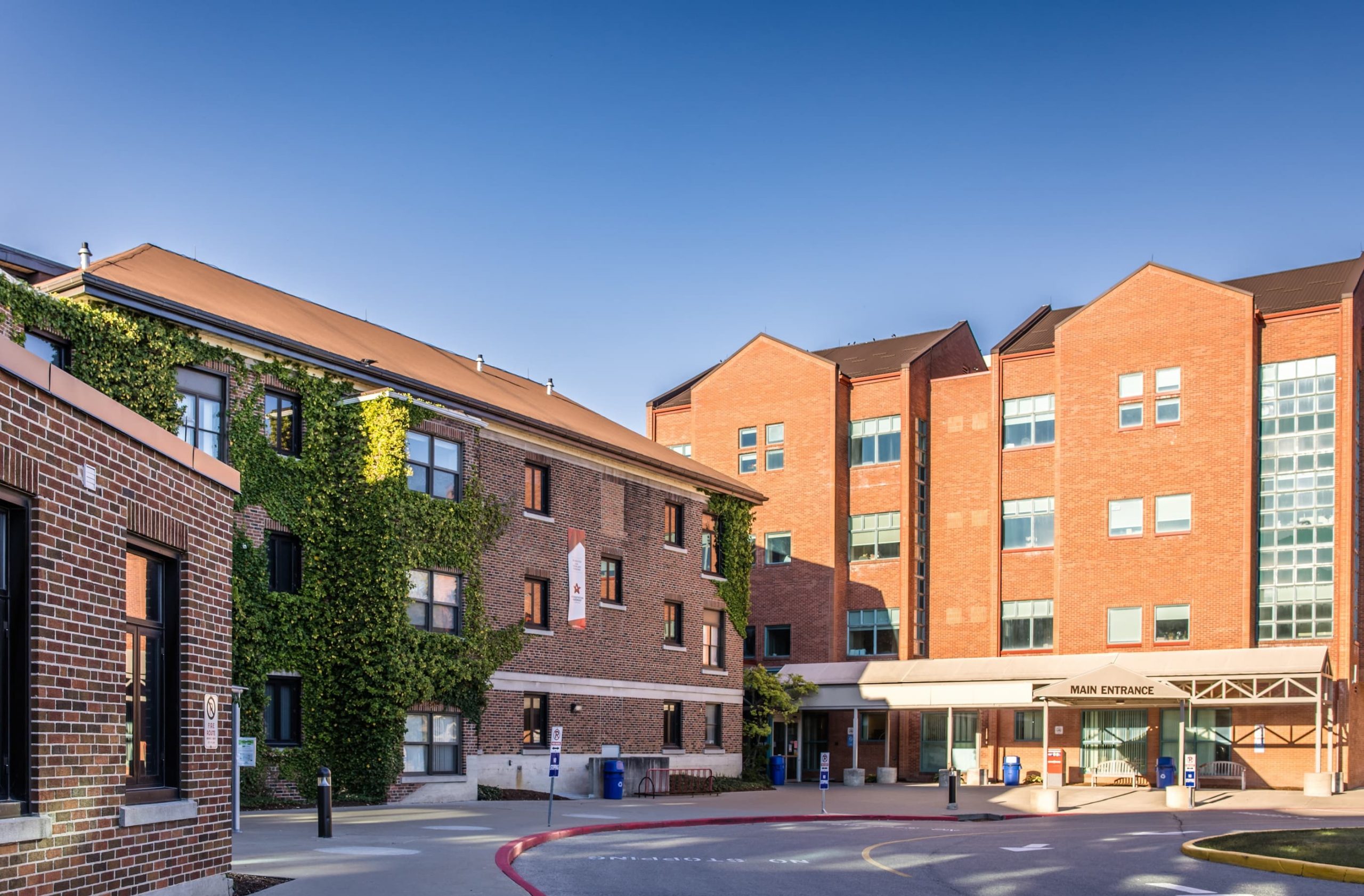 Exterior view of a brick hospital building with a main entrance and wheelchair accessible parking spaces.