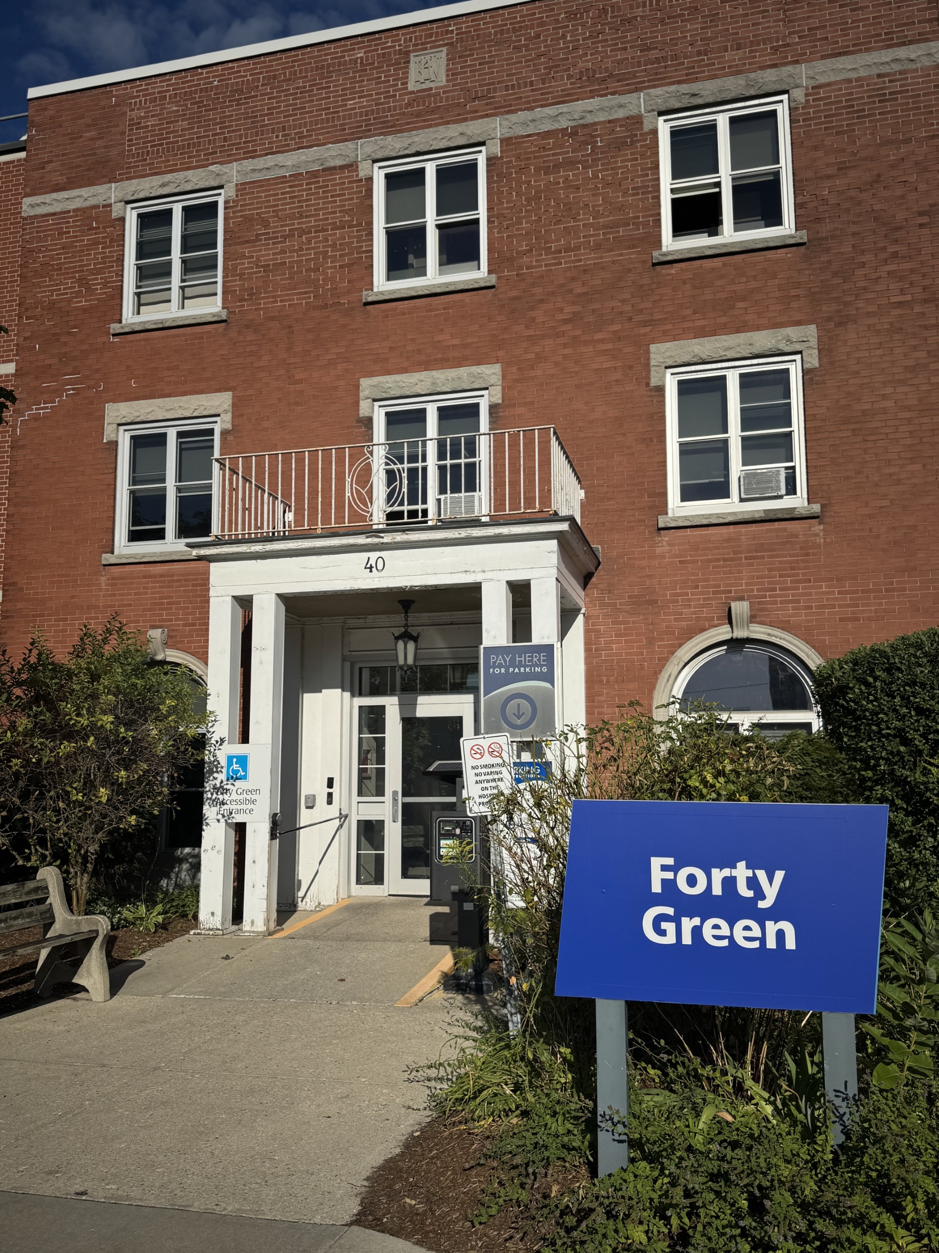 A three-story red brick building with a sign in front reading "Forty Green" and a visible wheelchair accessible entrance.